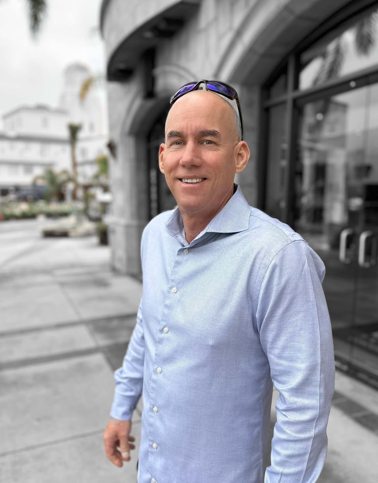 Carl Gregory in a blue shirt and sunglasses. Portrait-style photo.
