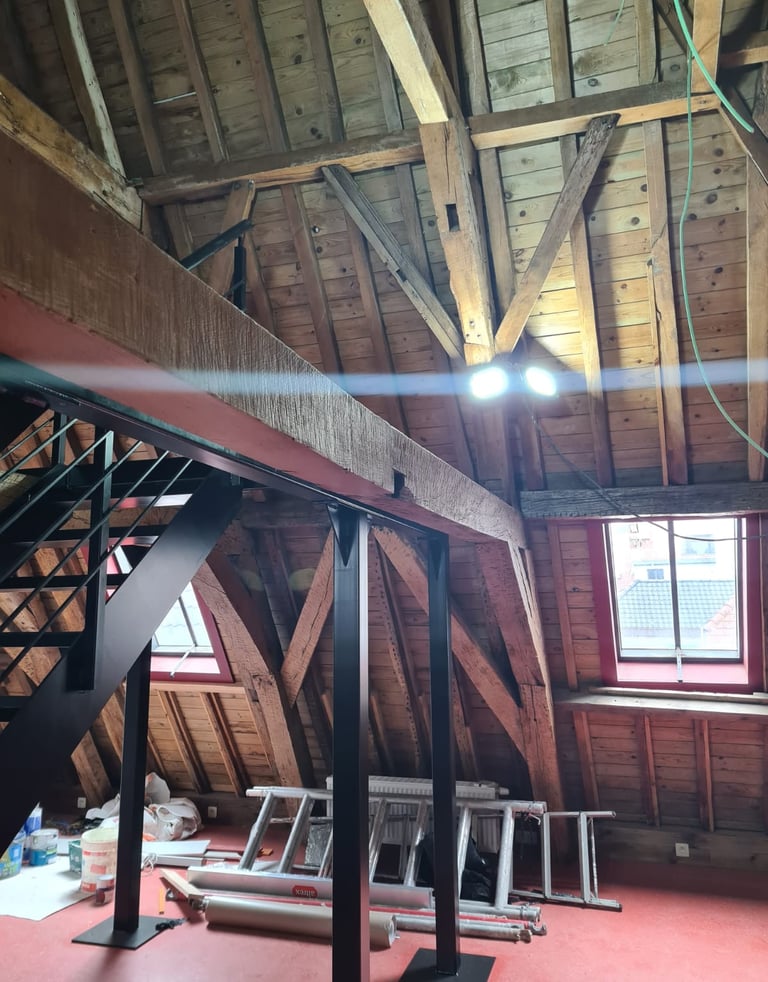 Ossature métallique avec escalier sur mesure, installée sous une charpente bois apparente dans des c