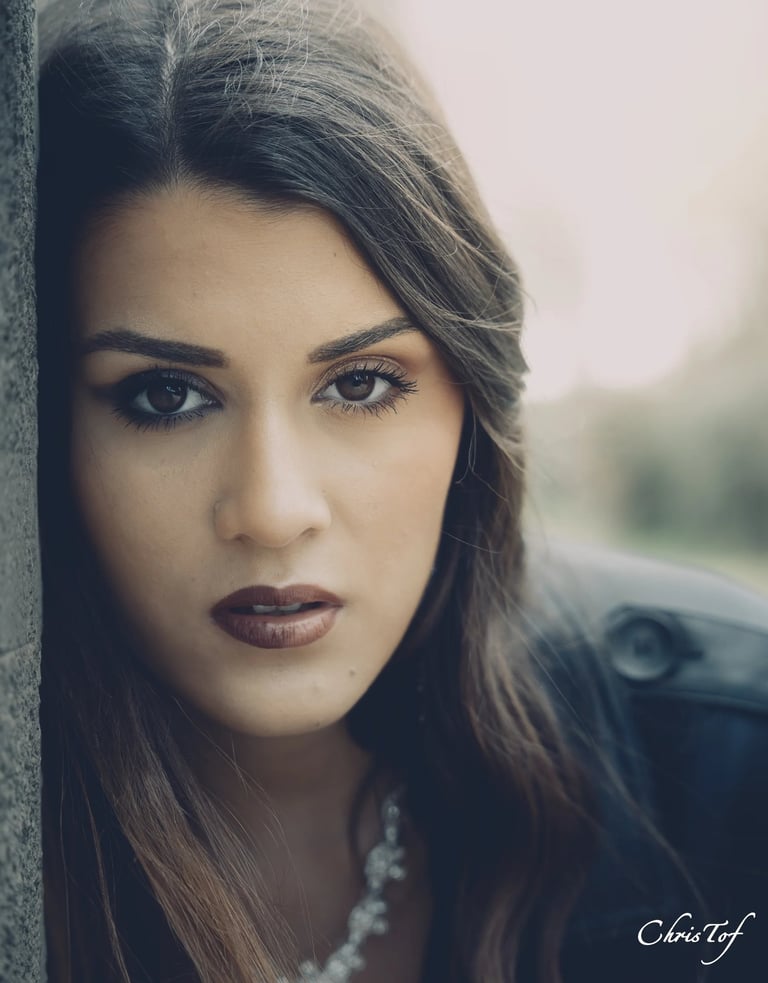 Shooting photo d'une jeune femme aux cheveux bruns longs, appuyée contre un mur.