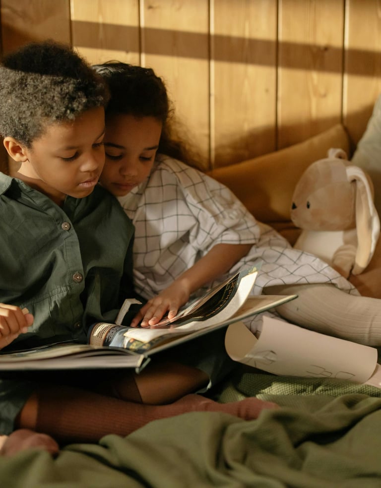 Deux enfants frères et soeurs assis sur un lit en train de lire