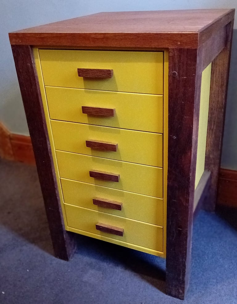 Bright yellow metal filing drawers with wooden handles with a wooden frame, legs and top