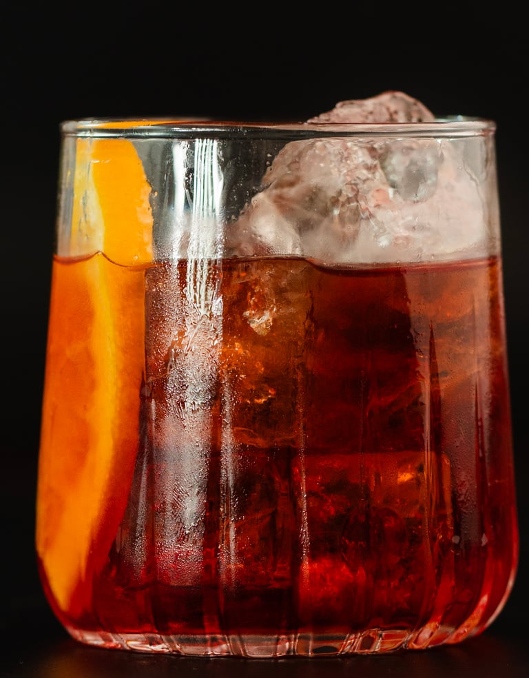 Klassischer Negroni-Cocktail mit Gin, Wermut und Bitterlikör, serviert auf Eis mit einer Orangensche