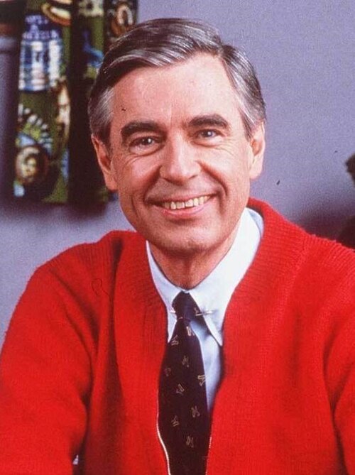 Mr. Rogers smiling in a red sweater and tie