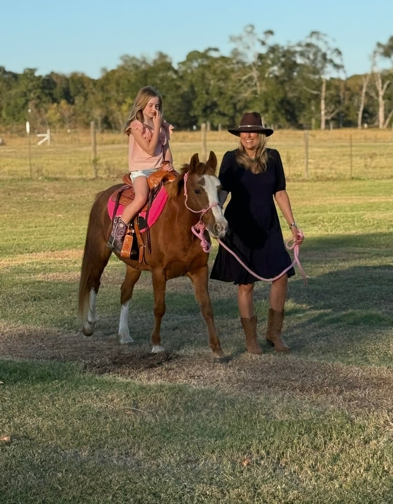 Pony Party owner hand leading Snickers the pony while a child rides