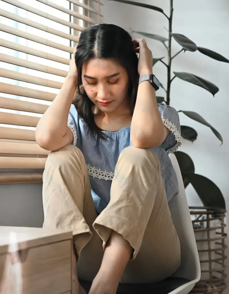 Girl sitting worried on a chair with hands around her head