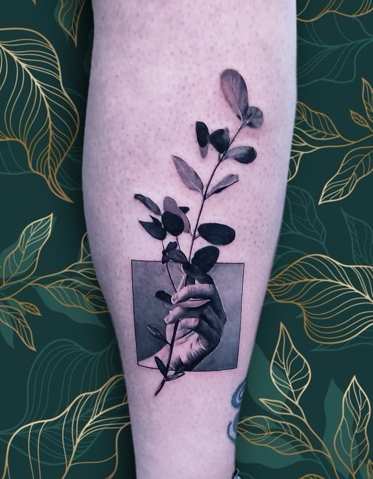 a person's hand holding a plant with leaves. custom piece by Katarsis Tattoo Perú.
