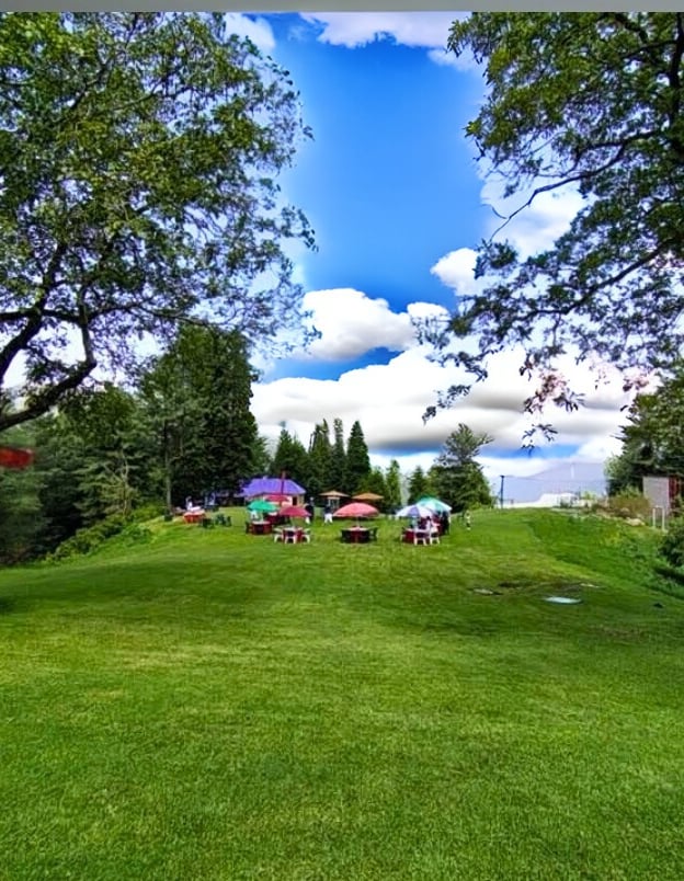 a grassy field with a few people walking around at Nathiagali
