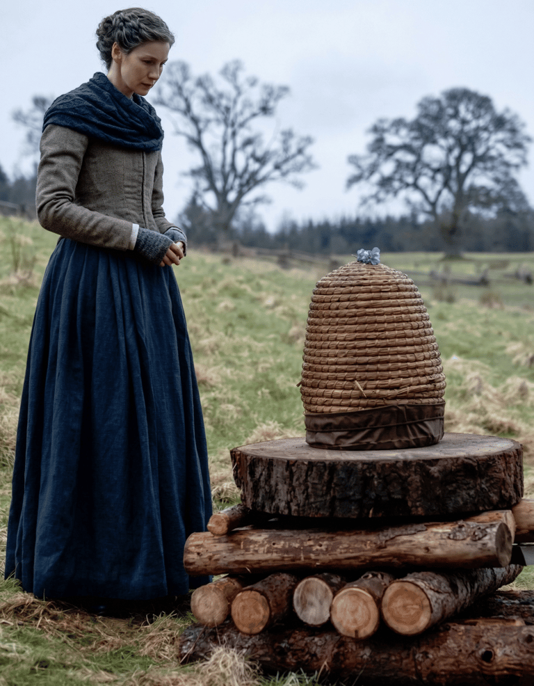 Escena inspirada en Outlander donde una mujer observa una colmena durante el ritual de contarle a las abejas una pérdida