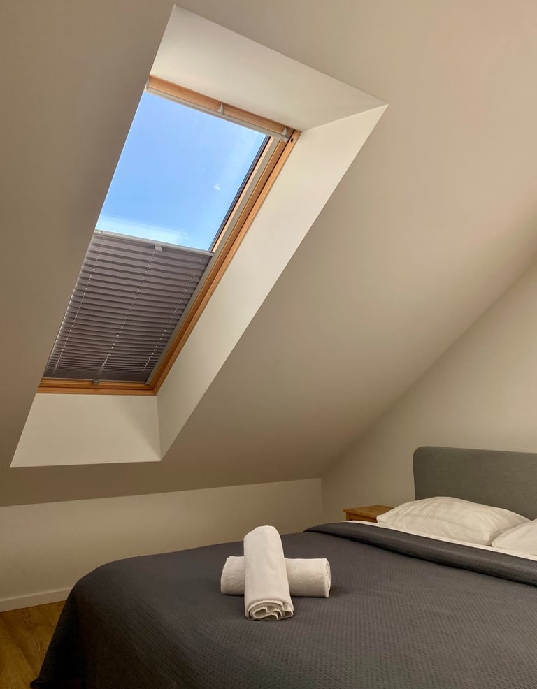 paveikslėlyje matyti plisuotos žaliuzės sumontuotos ant medžio spalvos stoglangio