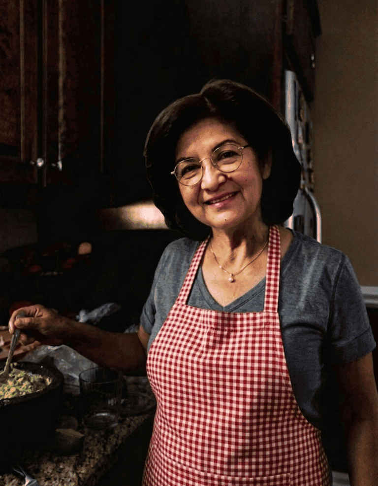 Señora con delantal de cuadros en una cocina preparando un platillo