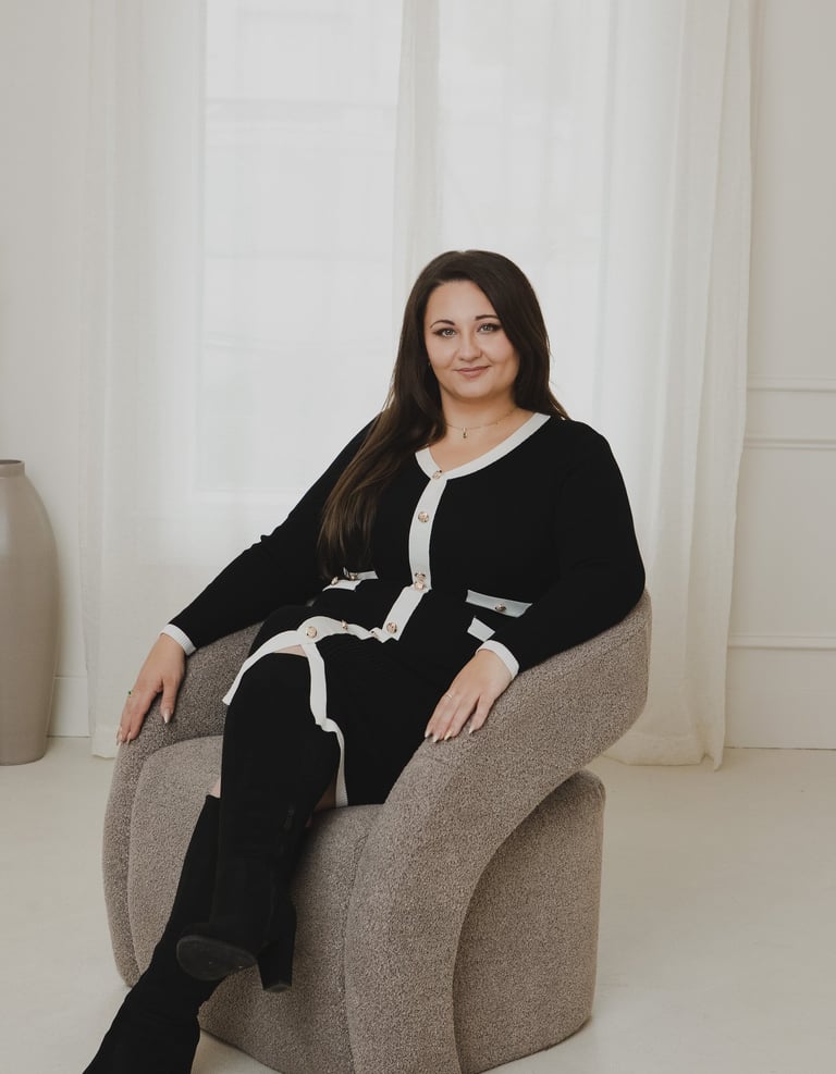 Adriana in black and white cardigan dress sits in a modern swivel chair for a professional portrait.
