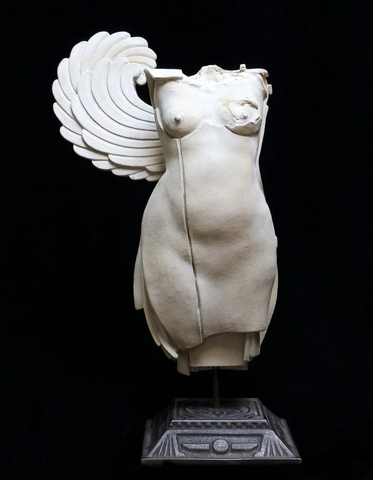 Small ceramic fragment of a female figure with a single wing and one disfigured breast.