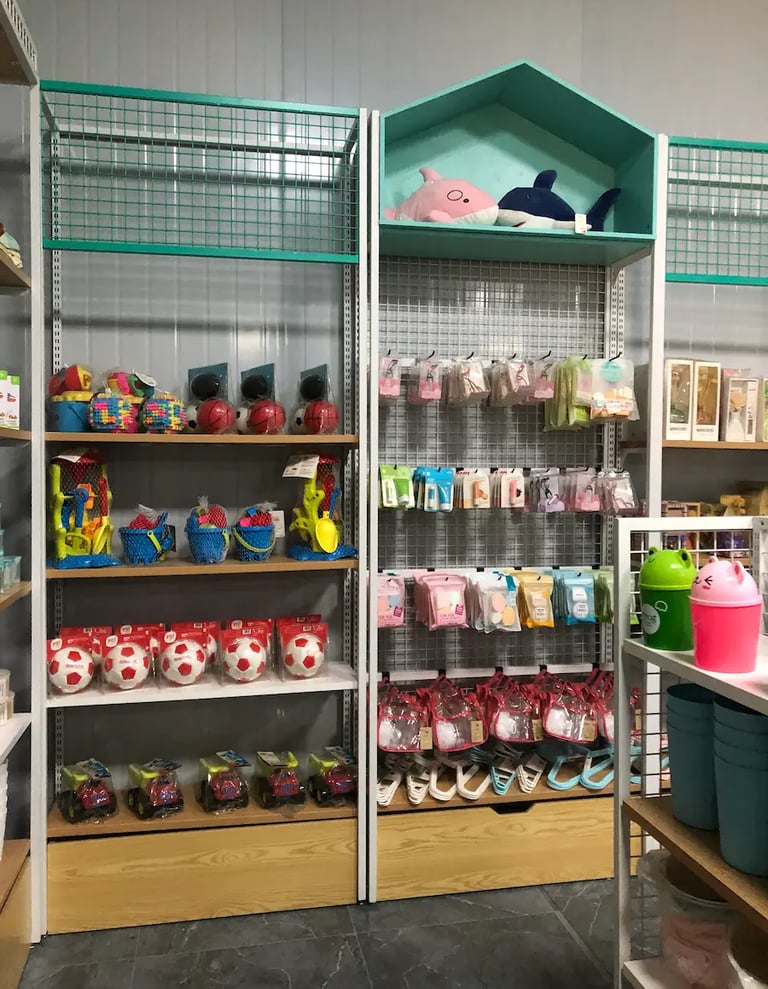 Retail store shelves displaying assorted children's toys, plush sharks, soccer balls, and colorful accessories.