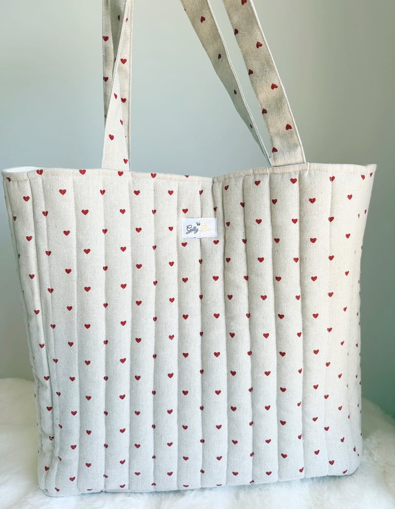 Quilted linen tote bag with red heart pattern and shoulder straps for daily use.