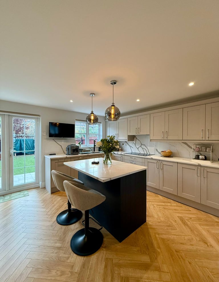 Modern shaker kitchen with grey cabinets, marble countertops, and a black island with bar stools.
