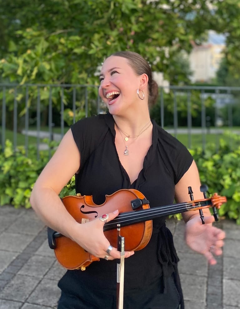Musician Evelyn Thom holding a fiddle and smiling.
