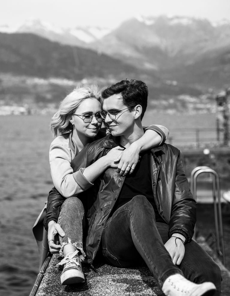 a man and woman sitting on a ledge overlooking the water