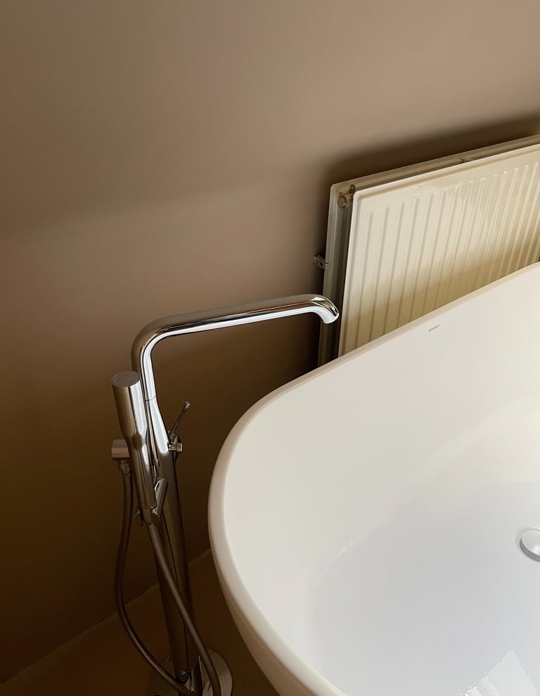 Vrijstaand bad met vloermontage badkraan en verticale radiator onder dakraam in moderne badkamer