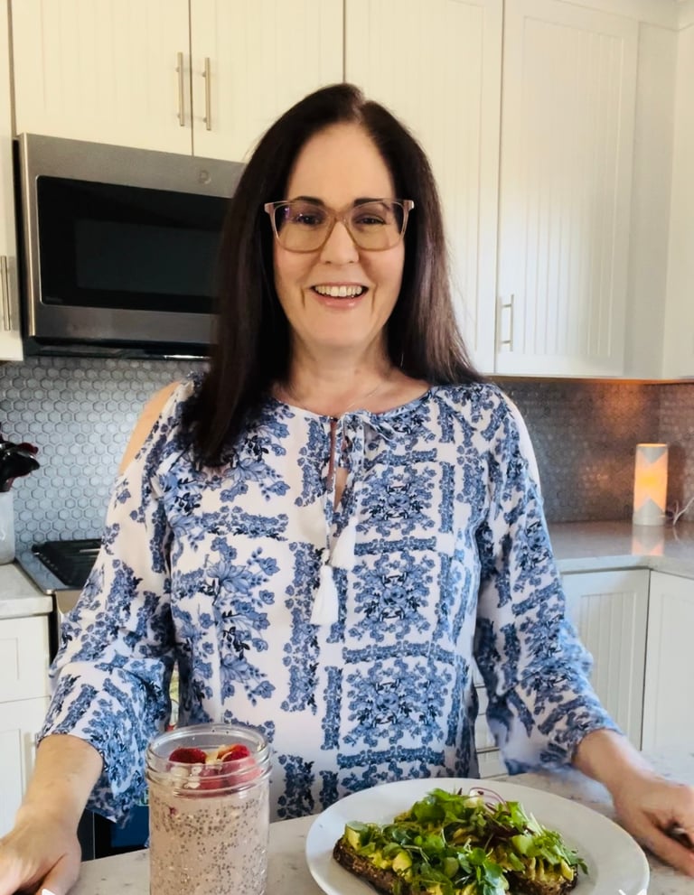 Woman standing in a kitchen with a plate of food and smoothie.