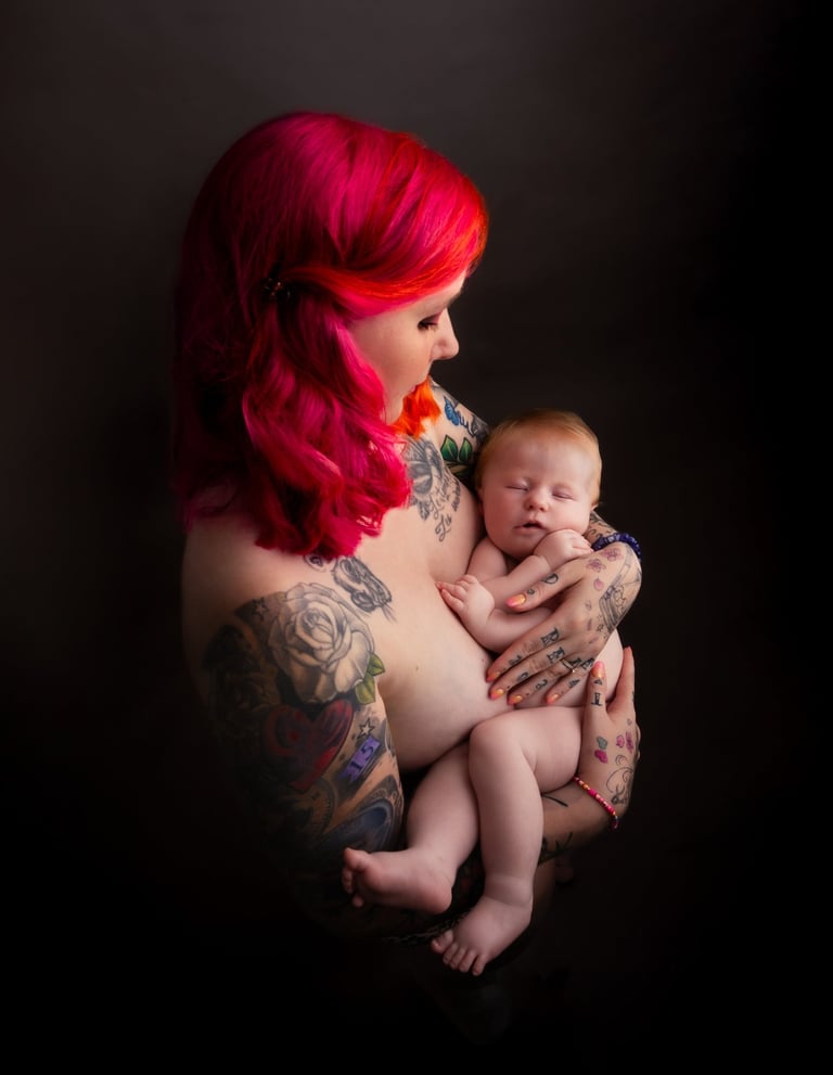 tattooed redhead woman carrying a baby