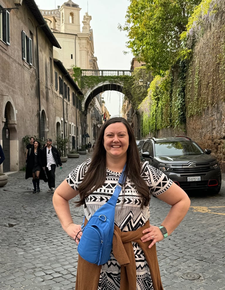 A woman standing underneath an archway on a cobblestone street in Rome, Italy