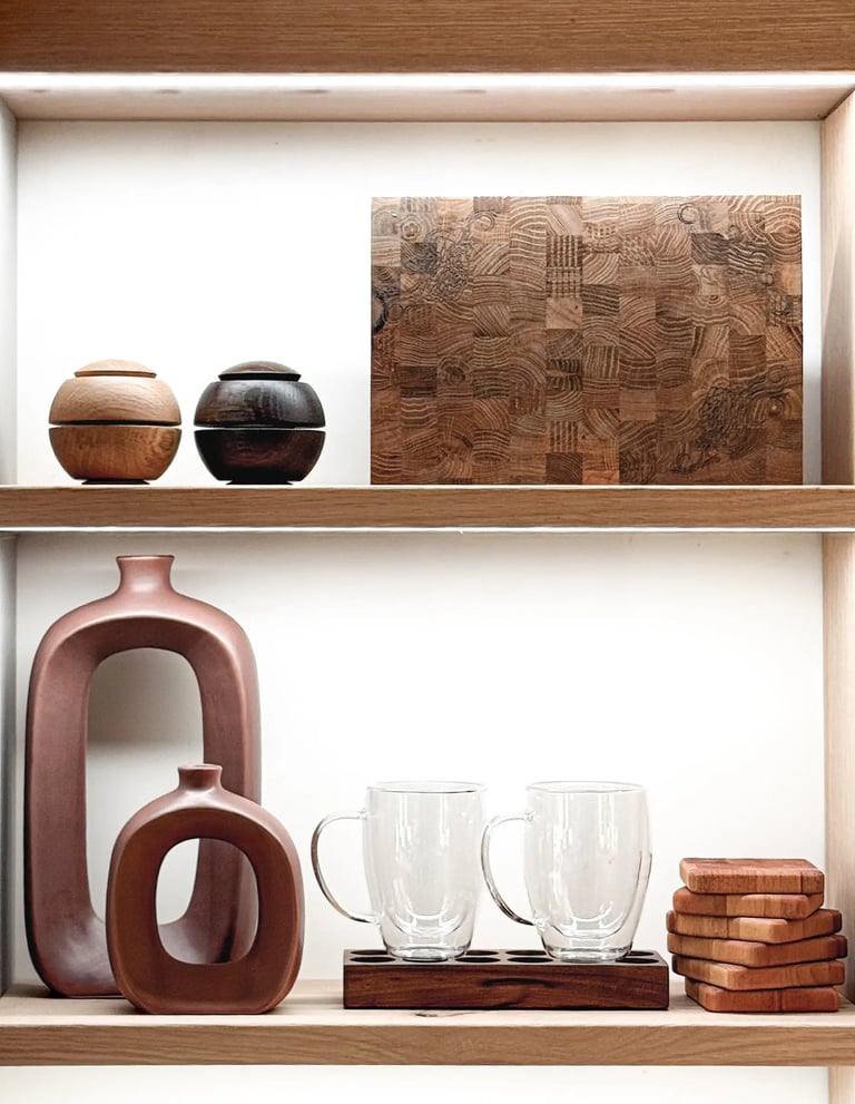 Styled wooden shelving featuring an end-grain chopping board, ceramic vases, glass mugs and coasters