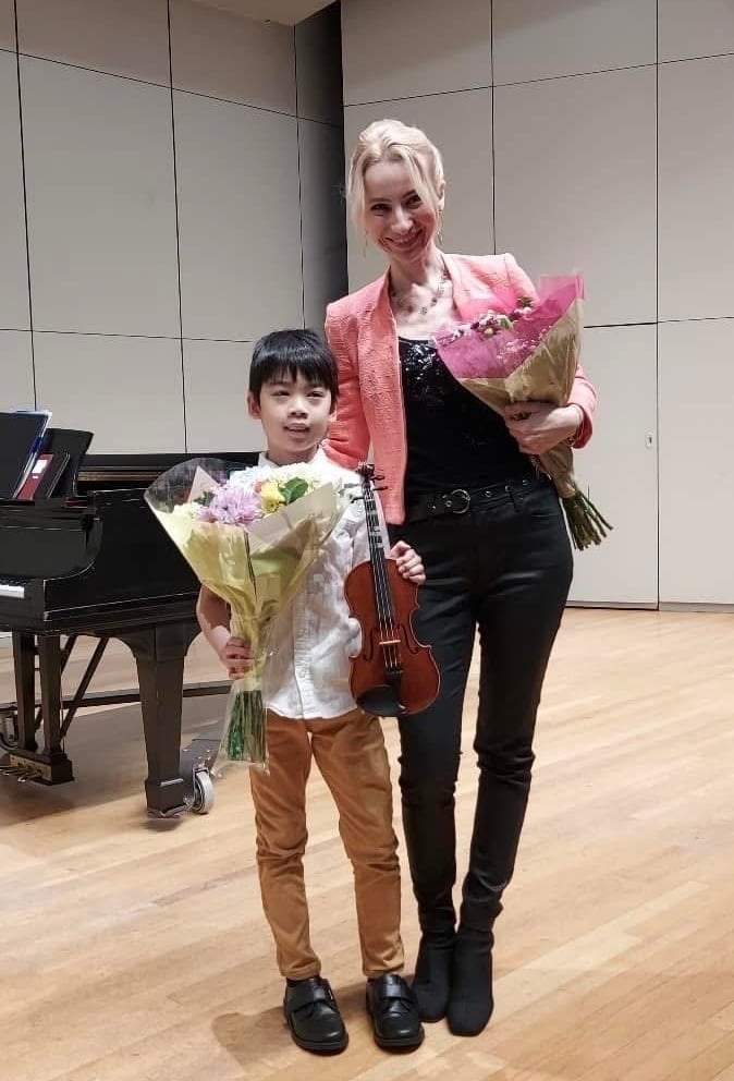 Violin student with his violin teacher after a successful concert
