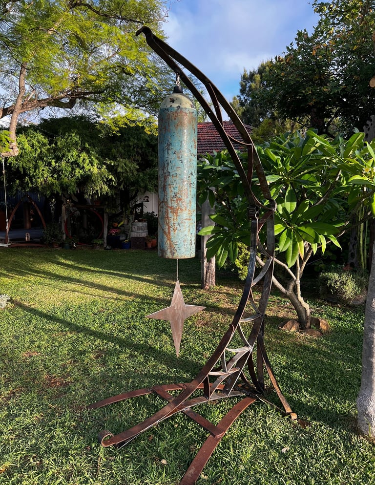 tall garden sculpture with large gong in shape of moon and star