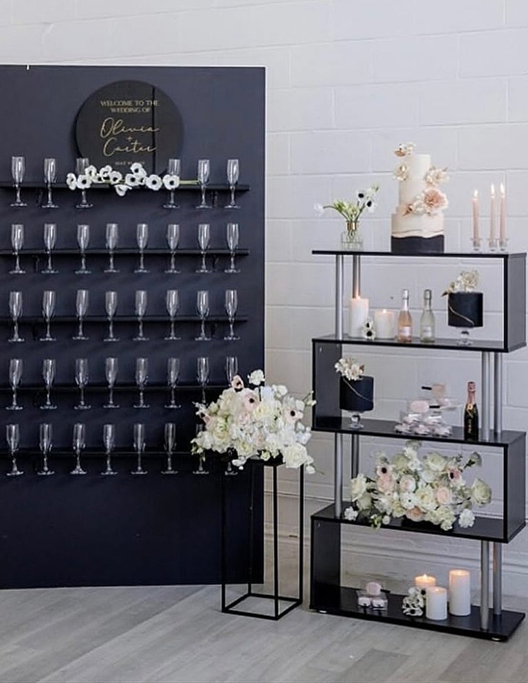 Black champagne wall with champagne flutes white floral. This set up was featured on wedluxe