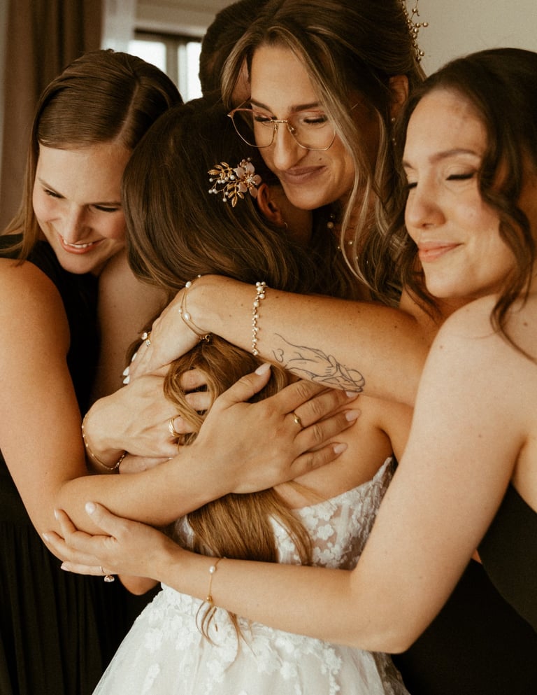 Quatre demoiselles d'honneur émotives qui enlacent une mariée