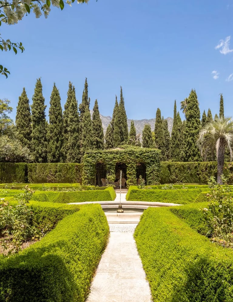 Formal rose garden with clipped hedges and mountain backdrop