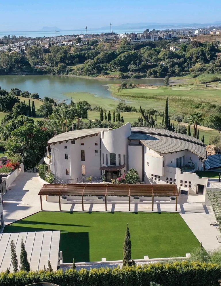 Luxury villa overlooking a golf course and lake in Marbella, Spain with scenic mountain views.