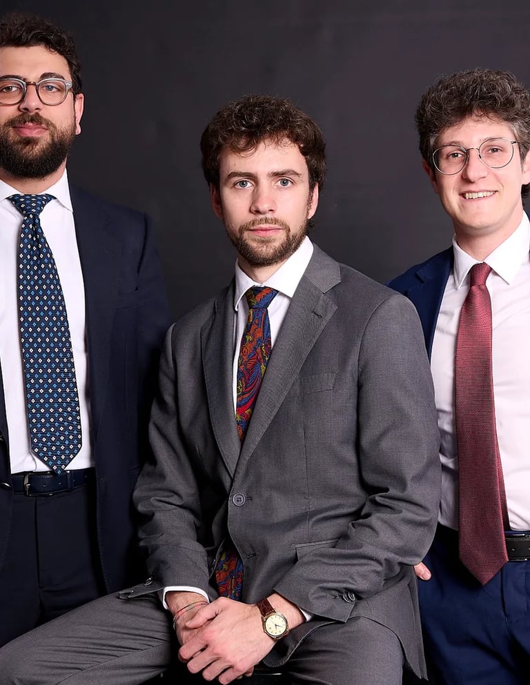 Three lawyers wearing formal suits and ties posing for a corporate group portrait.