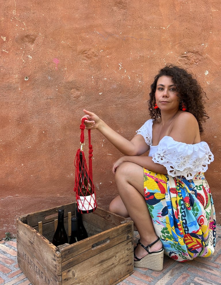 chica con una porta bolsa para el vino. Se ve la botella del vino también y la modelo esta agachada 