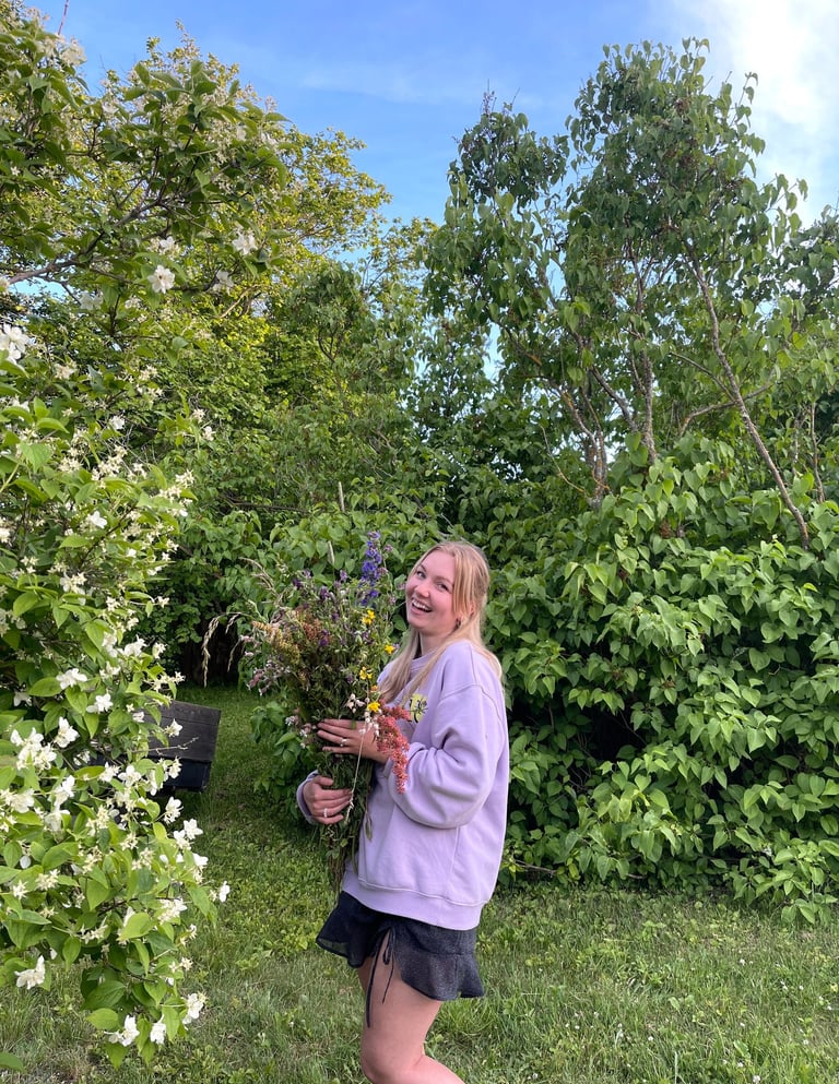 moteris apsirengusi violetiniu megztuku laiko gėles ir juokiasi