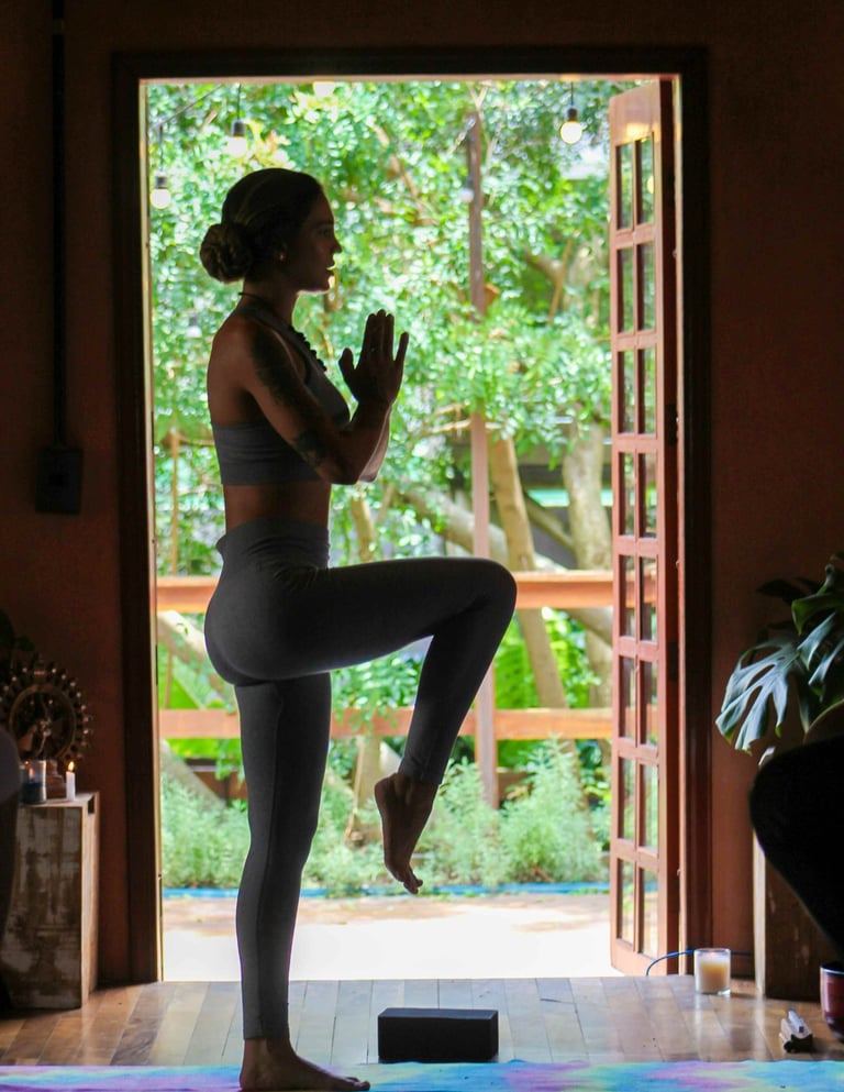 Frau übt Yoga vor einem Fenster mit Blick zum Garten