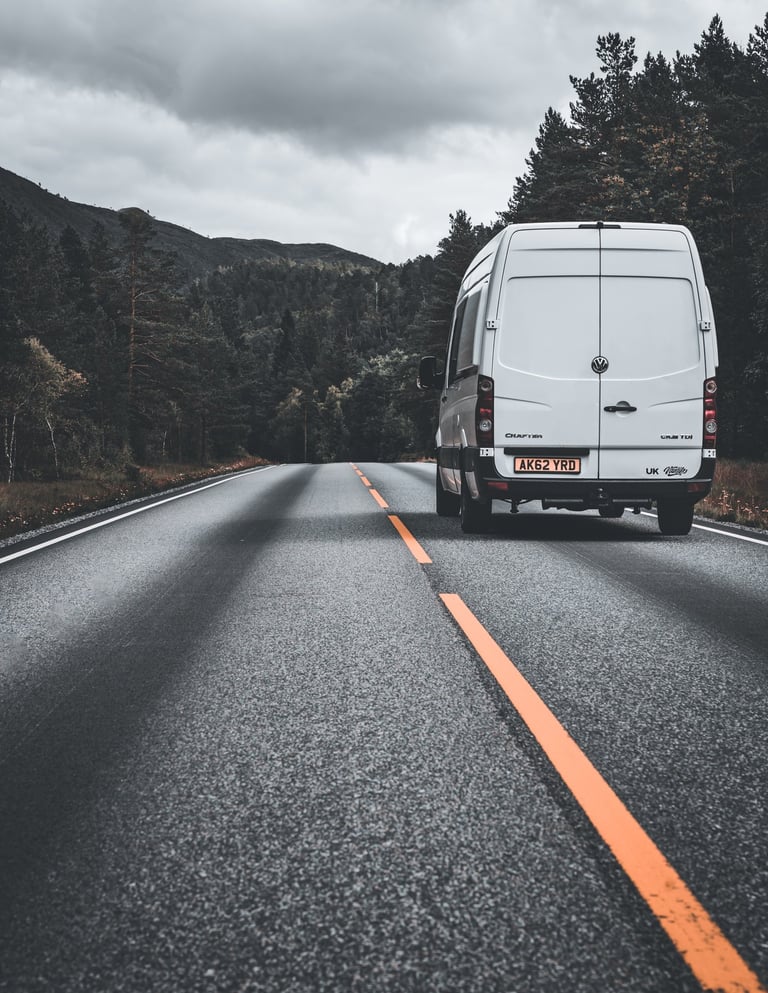 photo of camper van driving through forest in Norway
