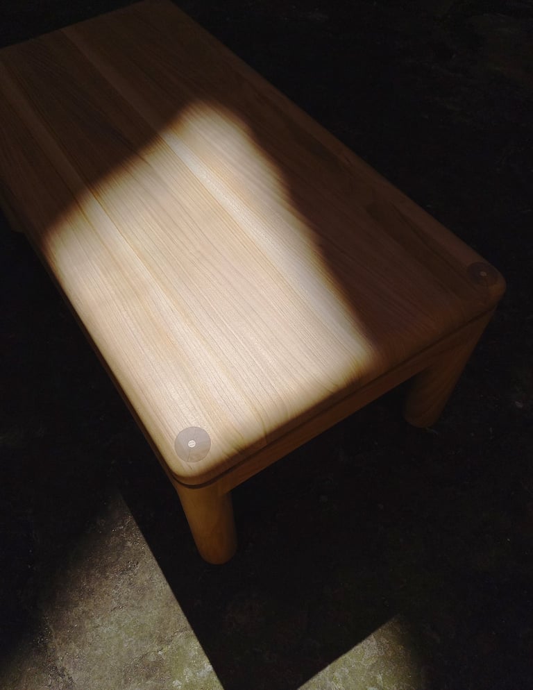 table basse en merisier aux angles et arêtes arrondis dans un rayon de soleil