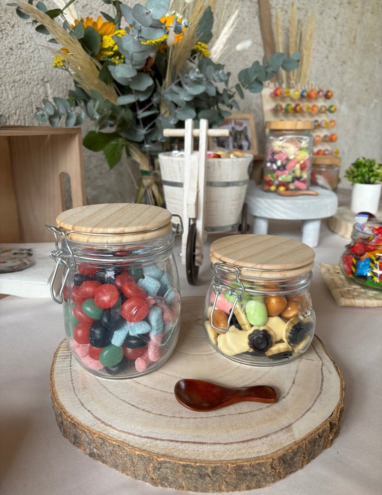 Bonbons dans des bonbonnières posées sur un dessous de plat en bois, candy bar