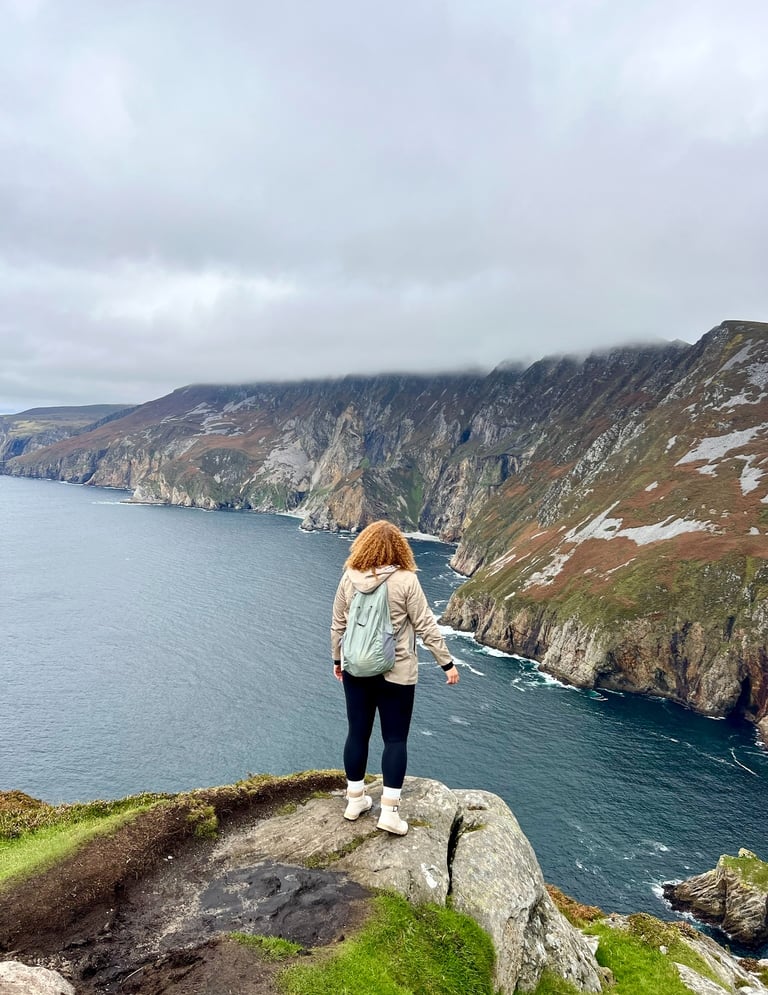 A hiker overlooks the Slieve League cliffs and Atlantic Ocean in County Donegal, Ireland.