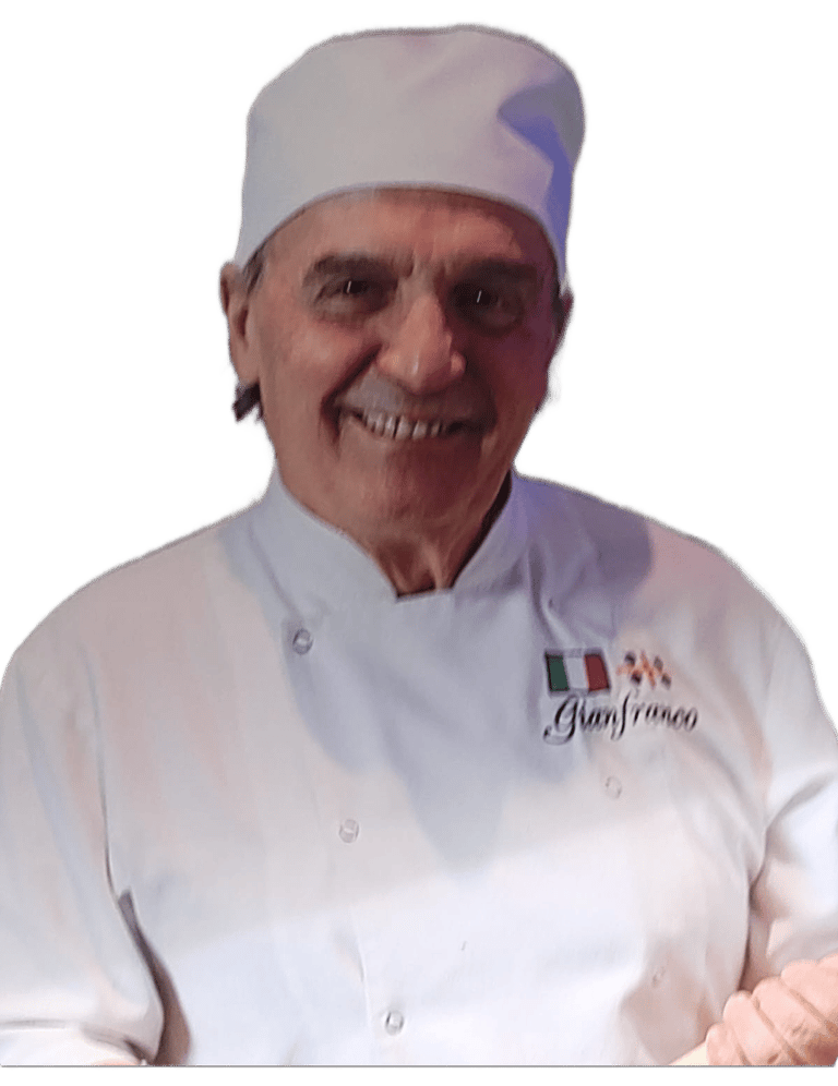 Smiling Italian chef Gianfranco wearing a professional white chef coat and toque hat.