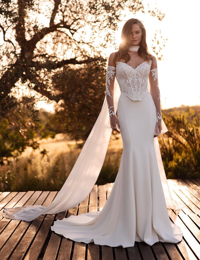 Elegant mermaid wedding dress with a lace corset bodice and long sleeves for an outdoor sunset ceremony.