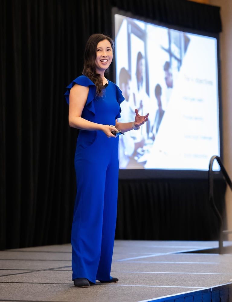 Unleashing Radiance speaker presenting confidently on stage in blue jumpsuit.