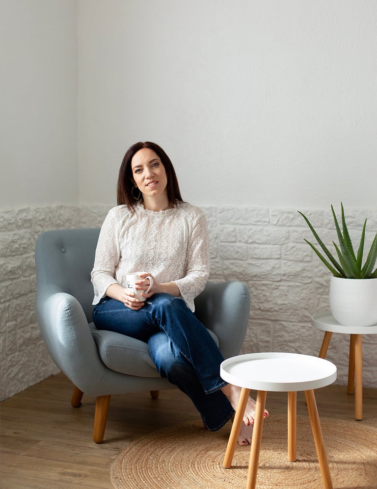 a woman sitting in a chair with a plant in front of her