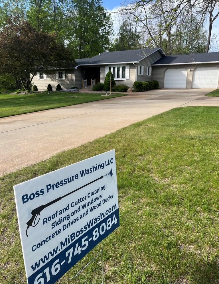 Boss Pressure Washing LLC yard sign in front of a freshly cleaned driveway and home.