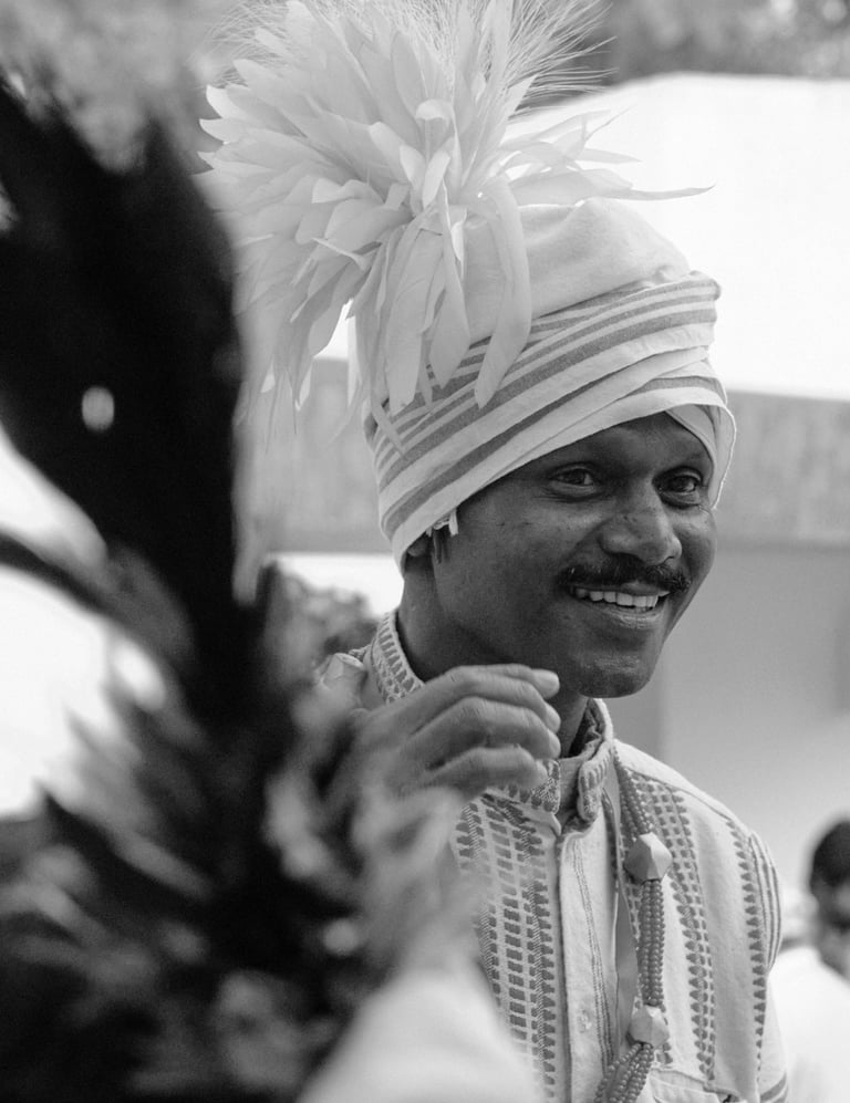 Smiling Indian man wearing a traditional turban and ethnic attire in a black and white portrait.
