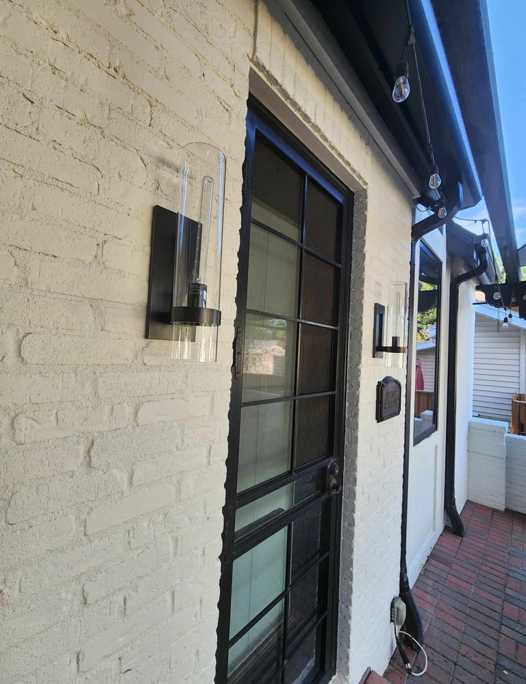 a small white brick building with a black door and a black door