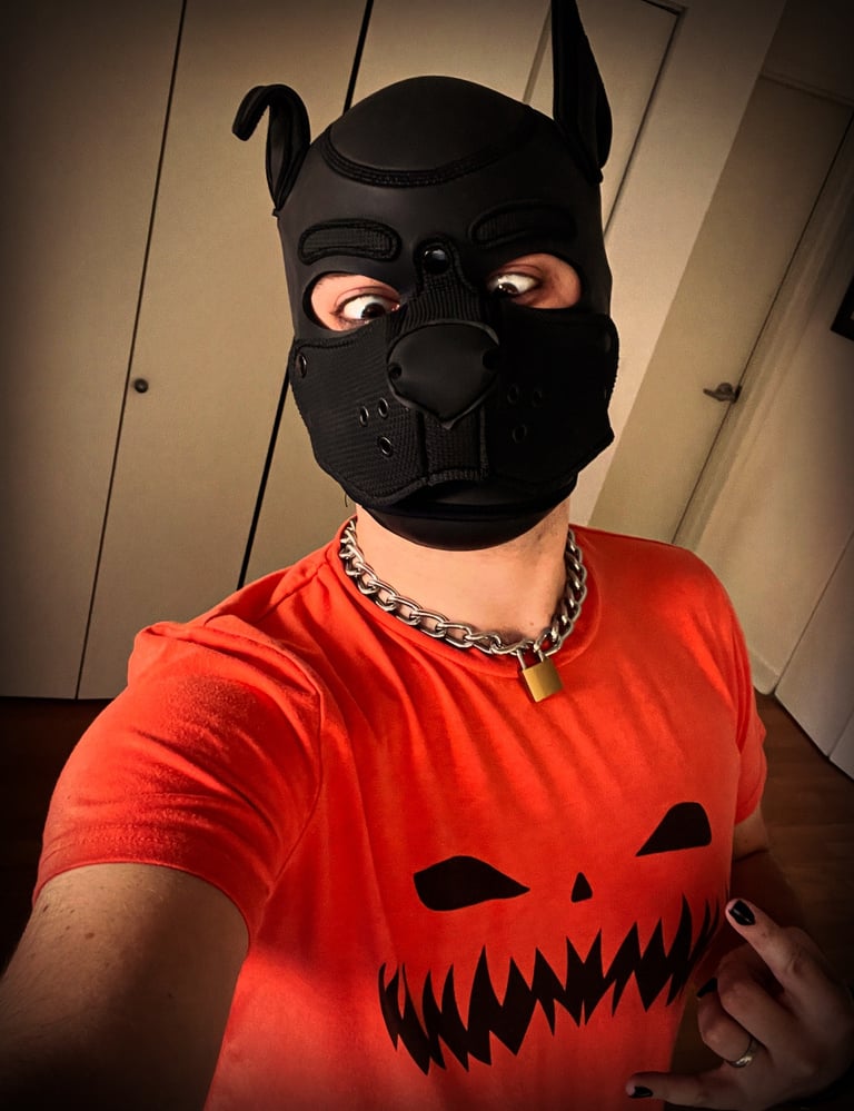 Man posing in pumpkin shirt and pup mask.