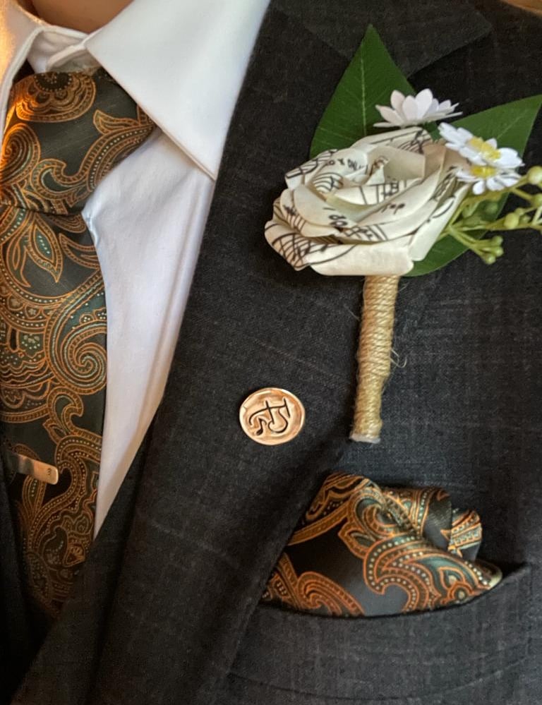 a man in a suit and tie with a flower made from music paper