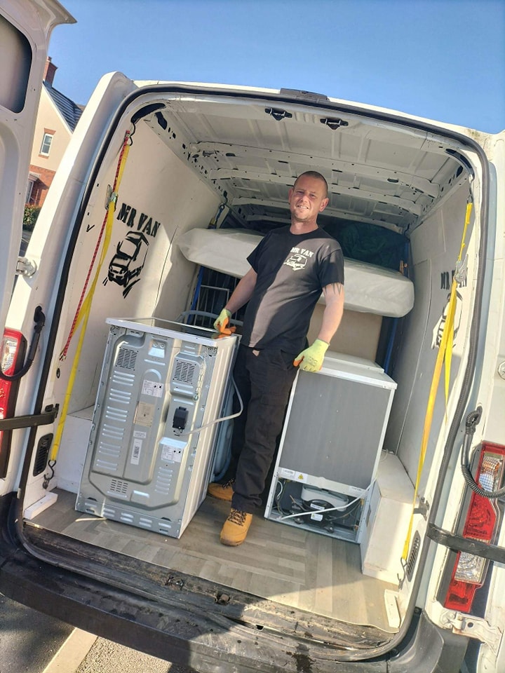 man stading next to washing machine in the back of van
